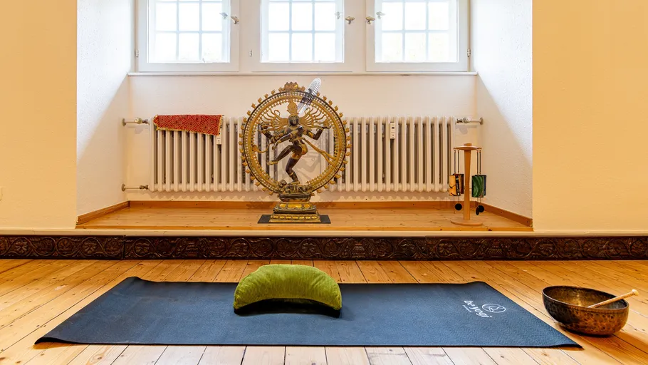 Yoga mat with statue and window behind.