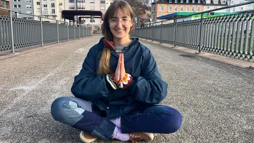 Person sitting cross-legged on urban bridge.