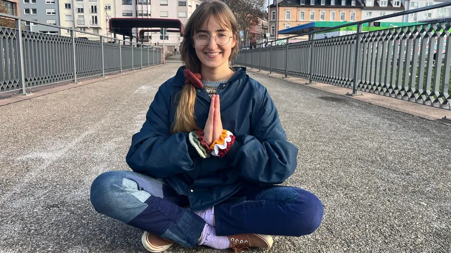 Person sitzt im Schneidersitz auf Stadtbrücke.