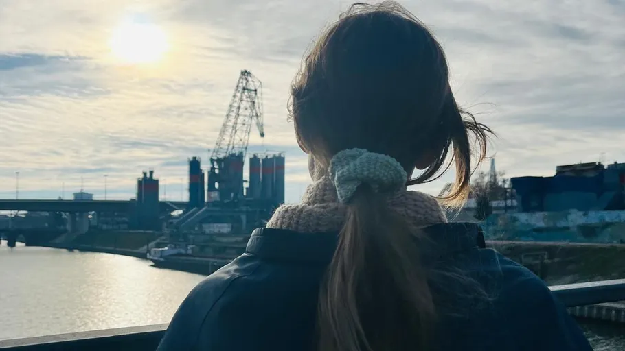 Frau mit Pferdeschwanz blickt auf Industriehafen.
