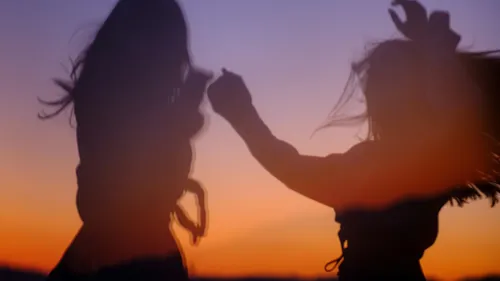 Two people dancing against a sunset backdrop.