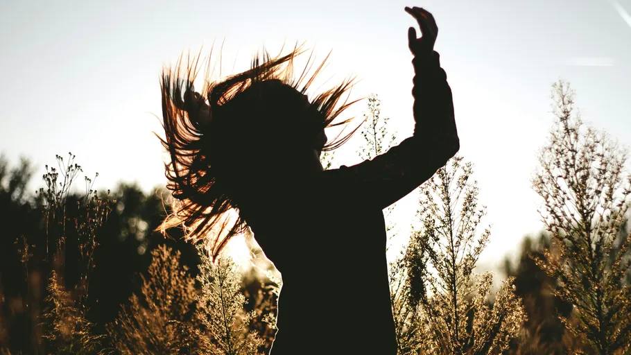 Silhouette of a person dancing in a field.