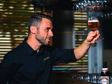 Man lifts a glass of beer in a bar.