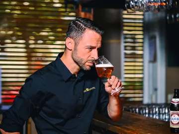 Ein Mann riecht nach einem Bier in einer Bar.