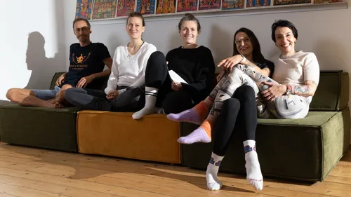 Five people sitting on a couch smiling indoors.