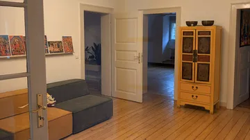Cozy room with artwork, sofa, cabinet, open doors.