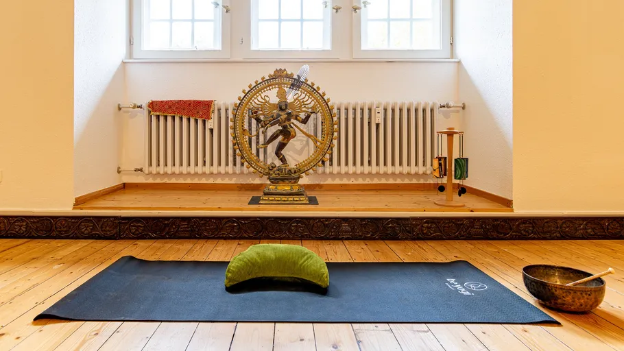 Yoga mat and cushion in serene room.