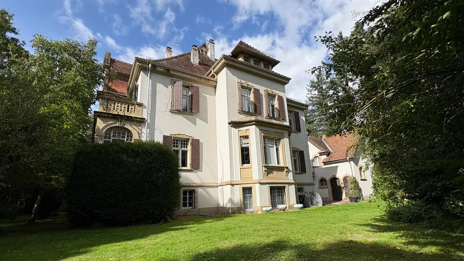 Großes Haus mit Garten unter blauem Himmel.