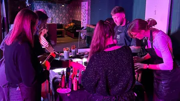 People painting at a table in a dim room.