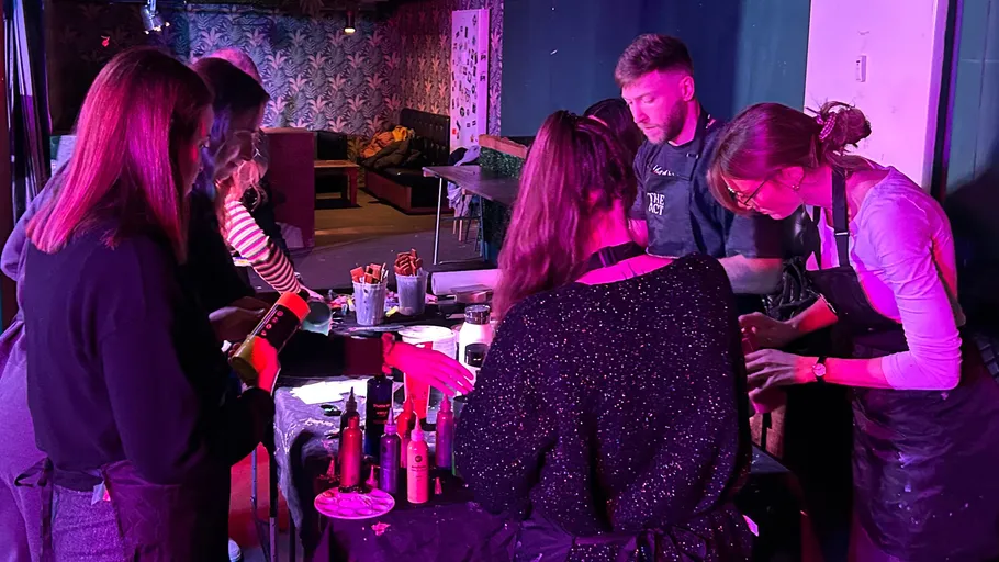 People painting at a table in a dim room.