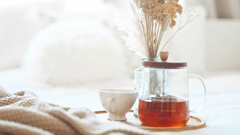 Tea pot and cup on wooden tray.