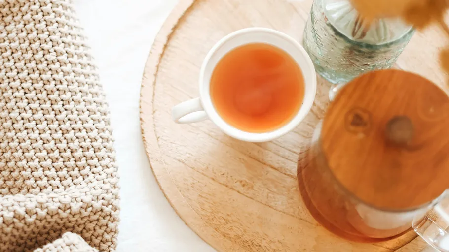 Cup of tea on wooden tray, cozy setting.