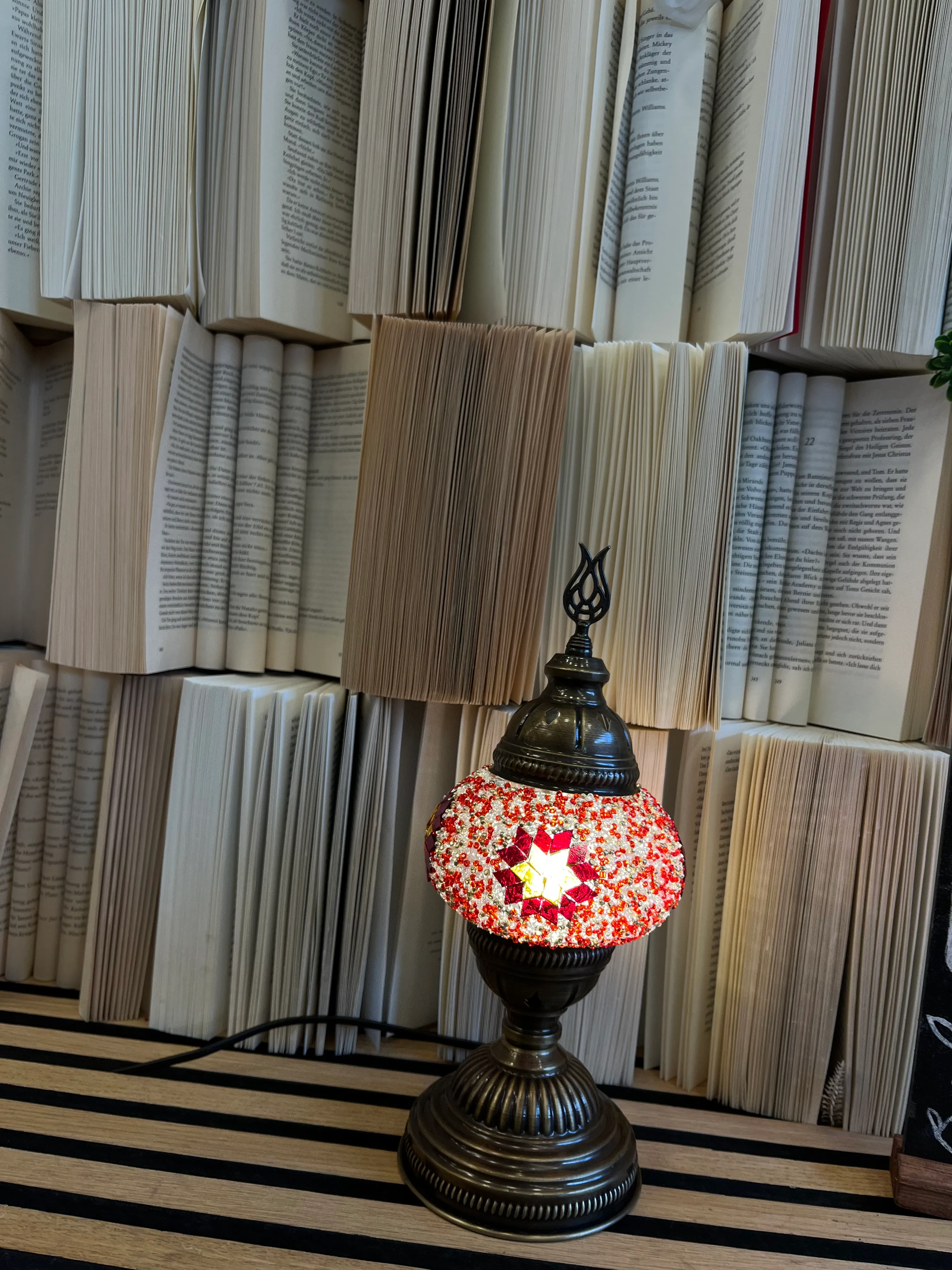 Dekorative Lampe auf Tisch mit offenen Büchern.