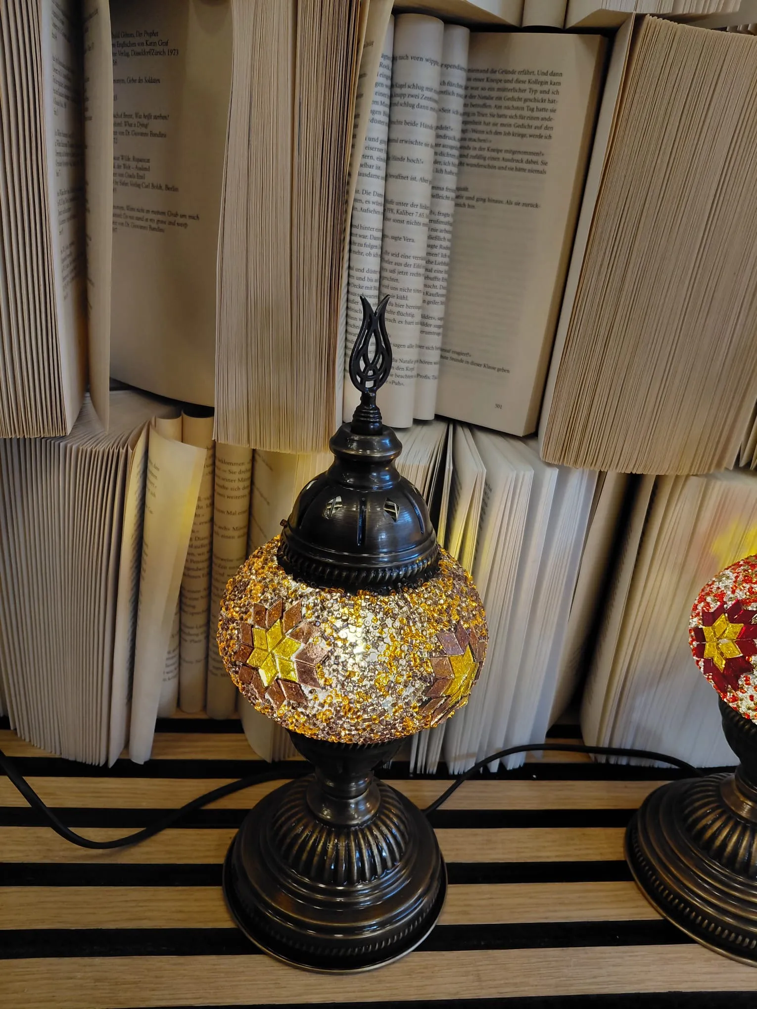 Mosaiklampe auf Tisch mit Büchern.