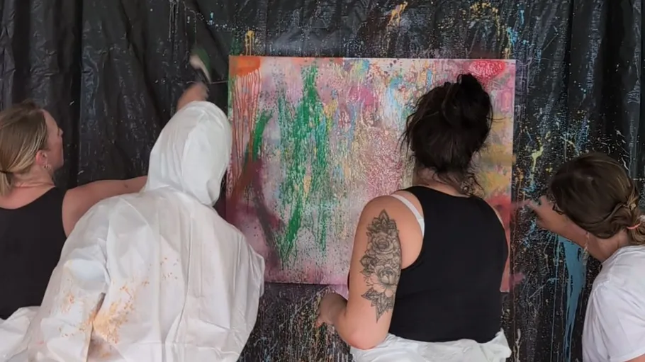 Four people creatively painting on canvas.