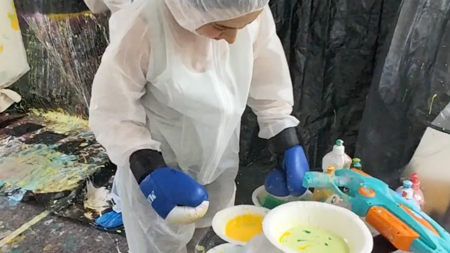 Person mixing paint in a protective suit.