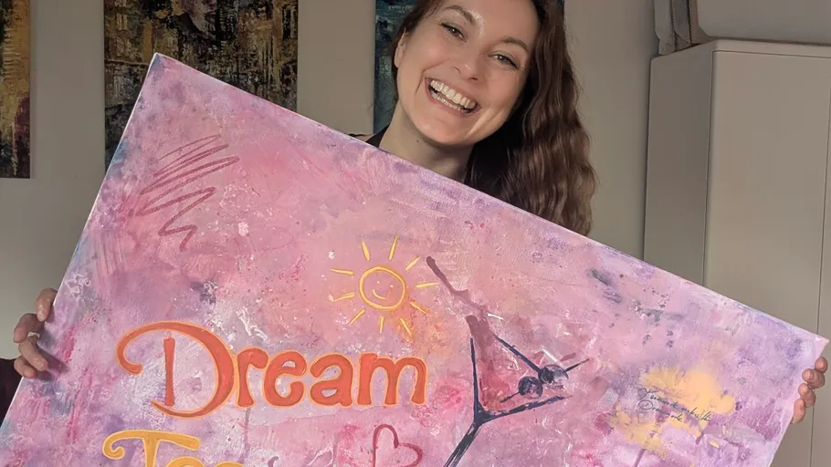 Smiling woman holds colorful art painting.