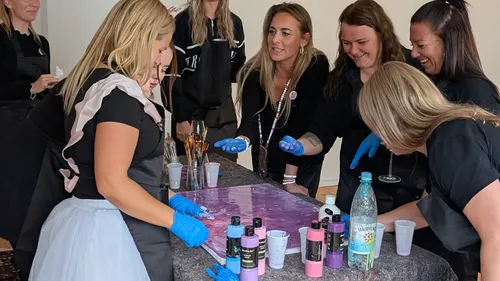 Women creating art on table, smiling together.