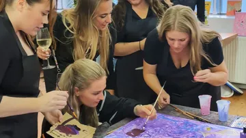 Gruppe von Frauen malen gemeinsam drinnen.