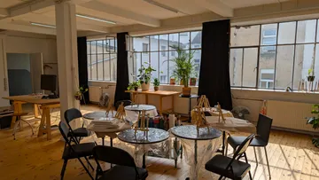 Kunststudio mit Staffeleien und Tischen.