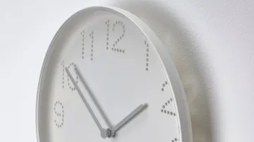Minimalist clock with dotted numbers on wall.