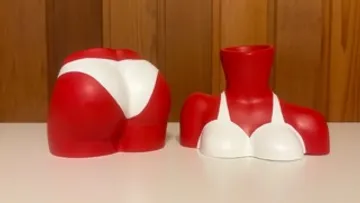 Two red and white torso sculptures on table.