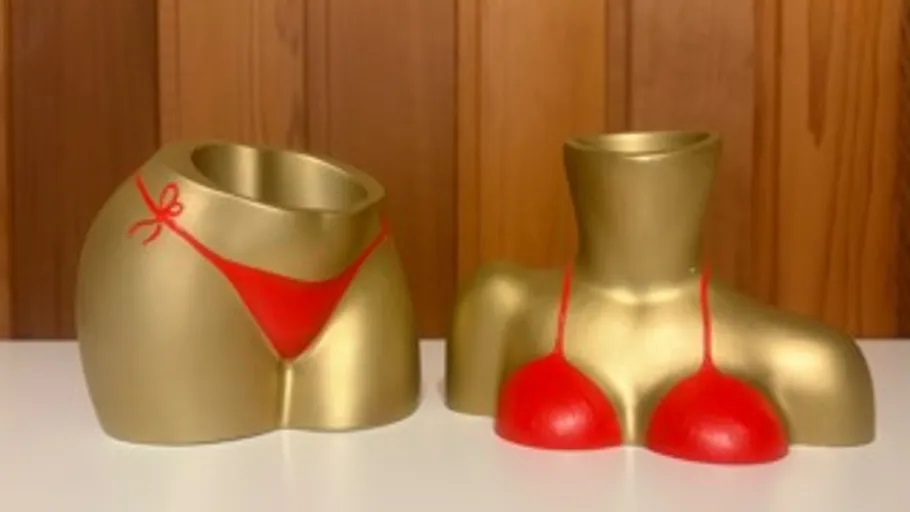 Gold body vases in red swimsuits on table.
