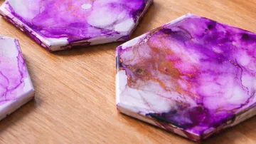 Purple marbled coasters on a wooden table.