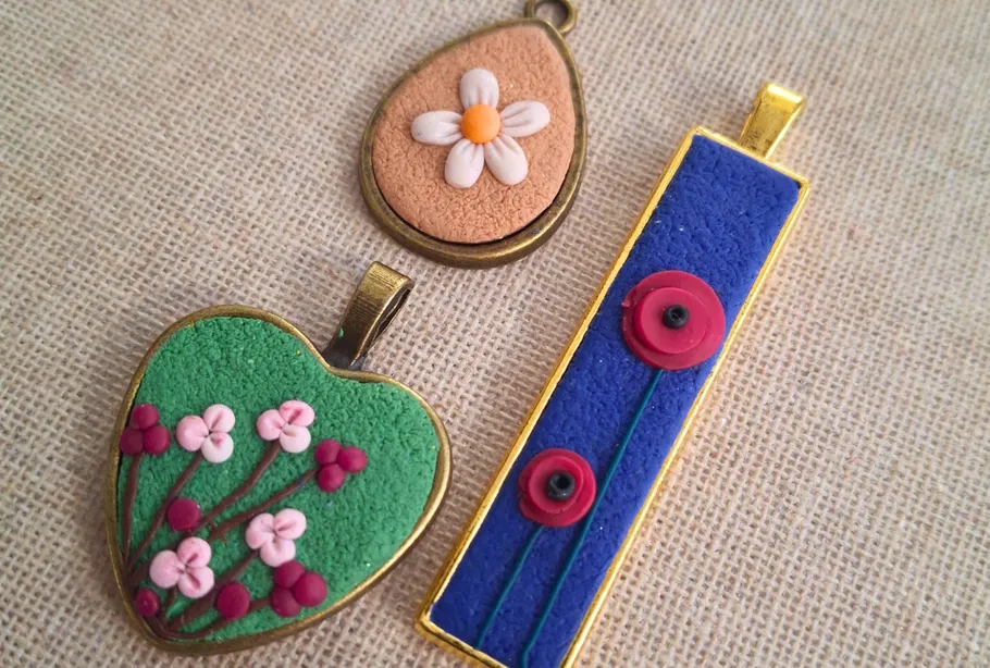 Three colorful pendants with flower designs on fabric.