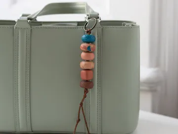 Colorful beaded keychain on light green bag.