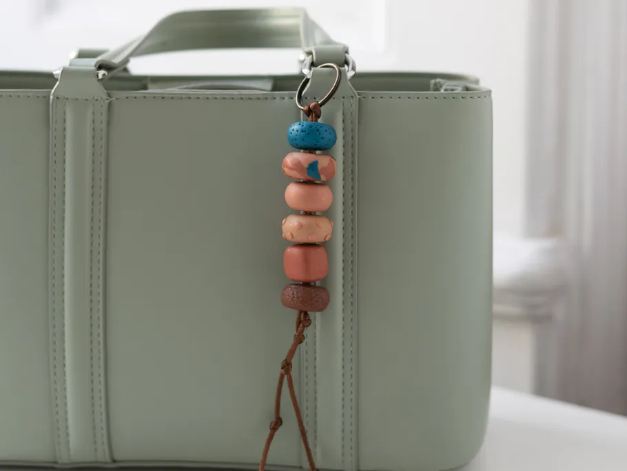 Bunter Perlen-Schlüsselanhänger an hellgrüner Tasche.