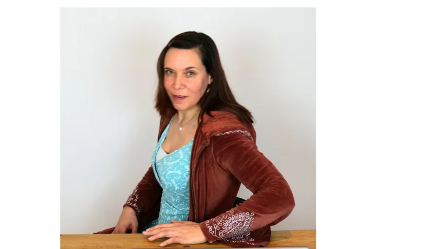 Woman sitting at table, wearing brown jacket.