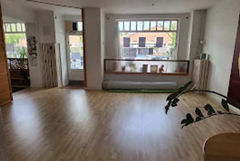 Spacious room with wooden floor, large windows.