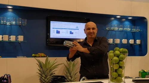 Man shaking cocktail shaker in modern kitchen.