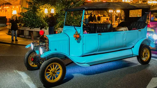 Blaues Oldtimer-Auto bei Nachtveranstaltung ausgestellt.