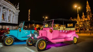 Colorful vintage cars parked at night.