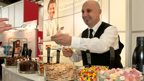 Man handing card at candy booth in event.