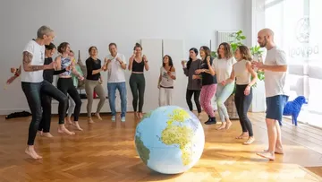 People dancing around large globe indoors.