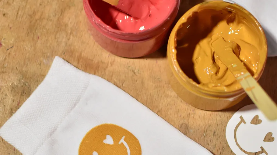 Painted emoji on cloth with jars of paint.