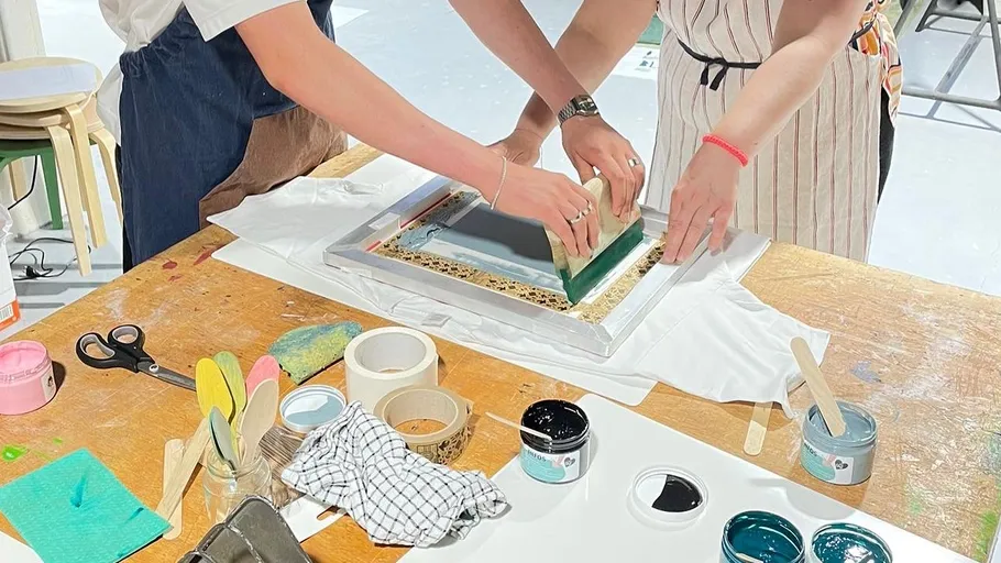 Two people screen printing on a table.