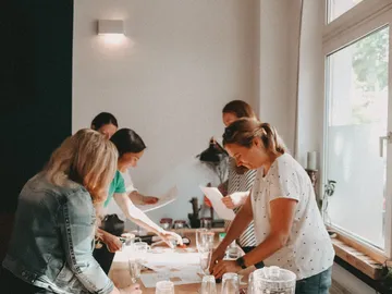 Frauen arbeiten an einem Tisch mit Papier und Gläsern.