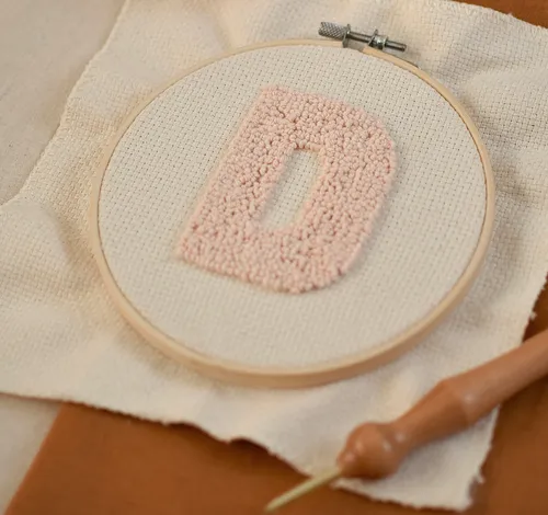 Embroidery hoop with letter D on fabric.