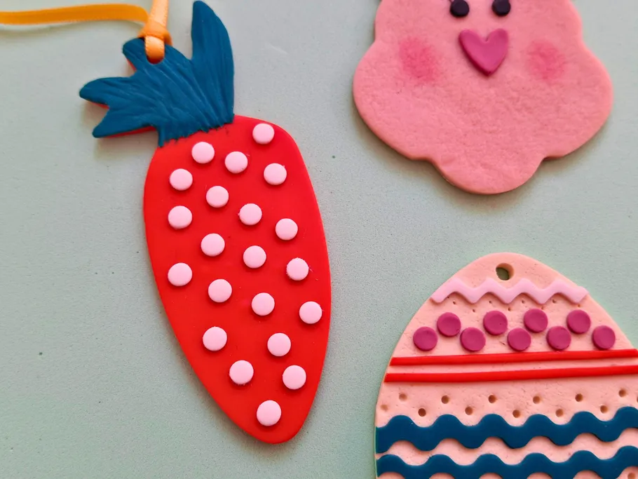 Three colorful clay ornaments on a surface.