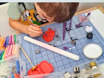 Kind bemalt Ton auf einem Basteltisch.