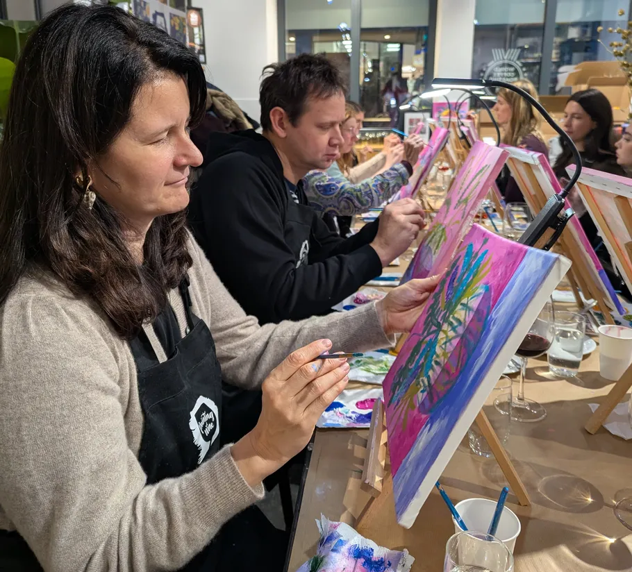 People painting on canvases in a classroom.