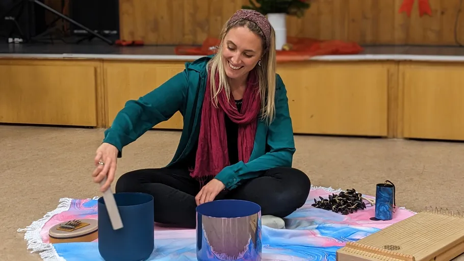 Smiling woman plays crystal bowls on stage.