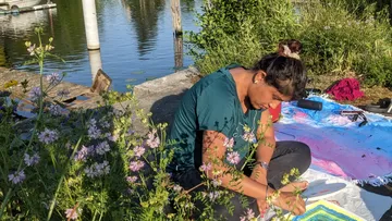 Person painting outdoors by a lake.