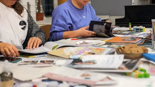 Menschen basteln mit Zeitschriften am Tisch.