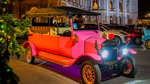 Vintage pink car parked on city street.