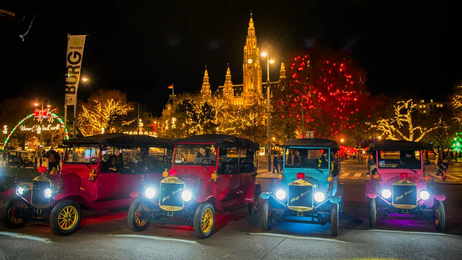 Oldtimer parken, Weihnachtsbeleuchtung, Stadt im Hintergrund.